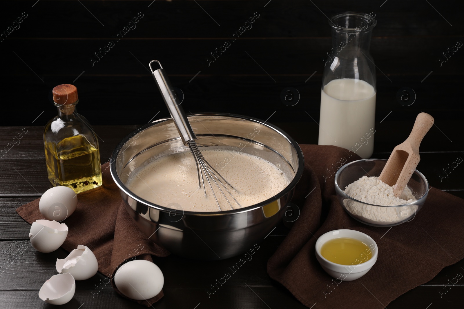 Photo of Composition with whisk and dough in bowl on wooden table