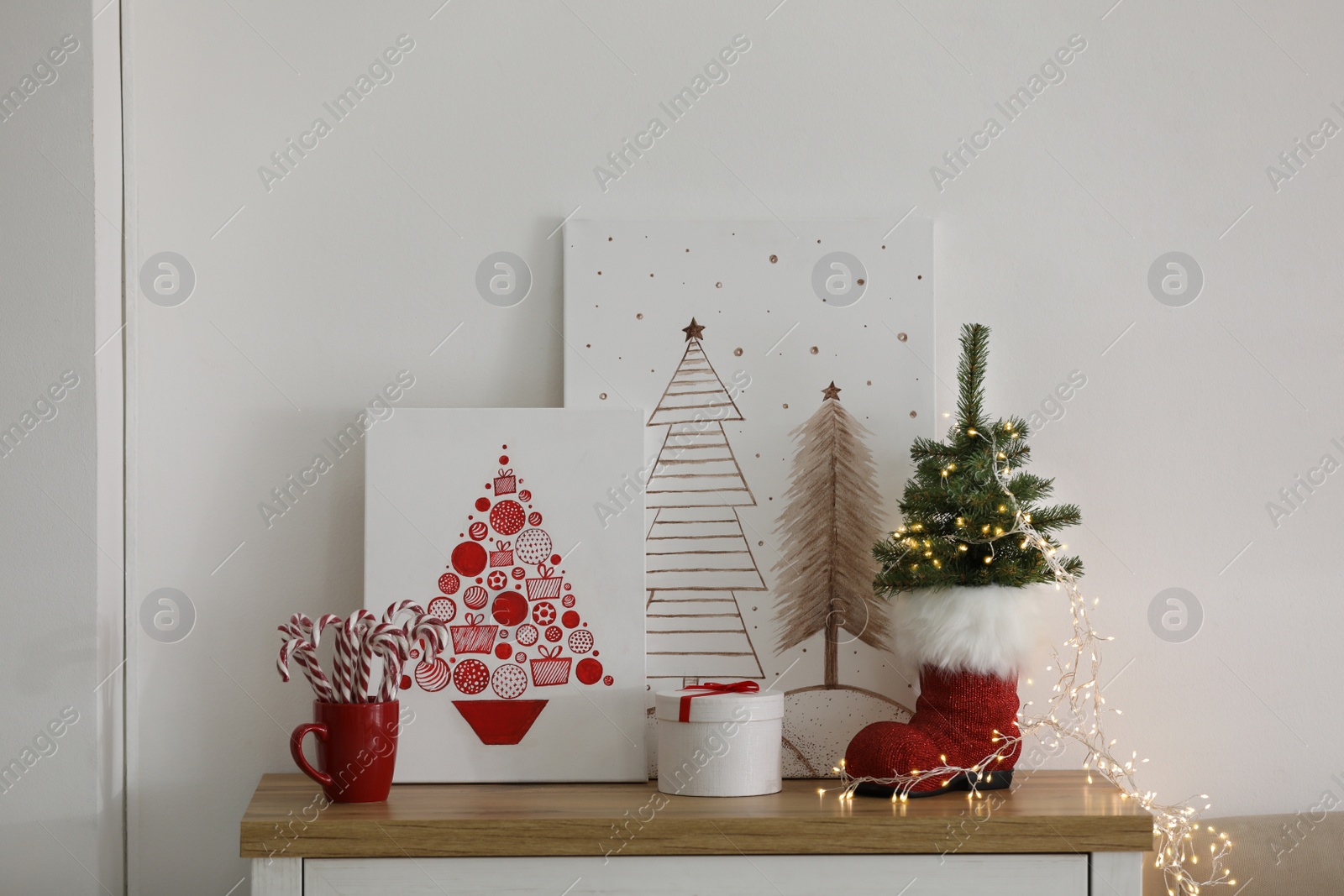Photo of Beautiful Christmas pictures on chest of drawers indoors. Interior design