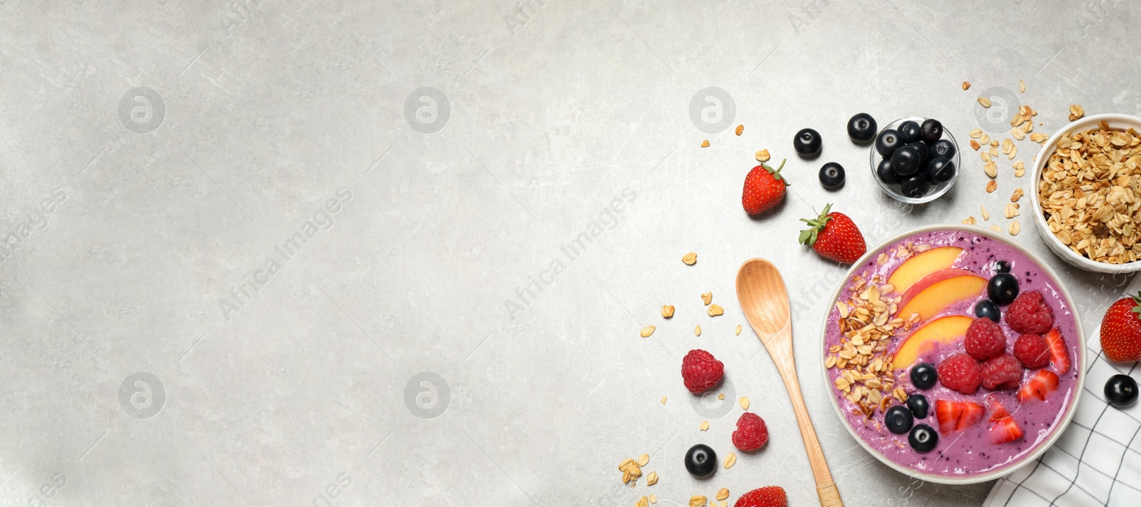 Photo of Delicious acai smoothie in bowl and ingredients on light grey table, flat lay. Space for text