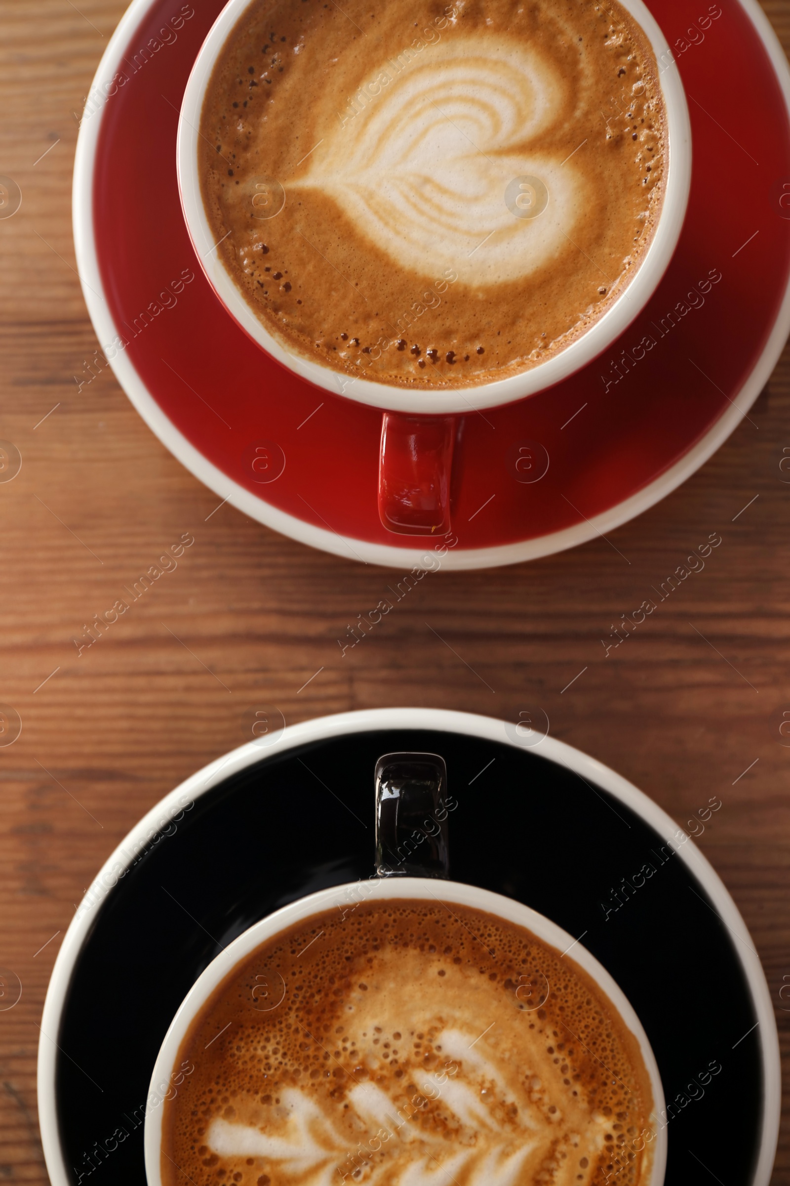 Photo of Cups of fresh aromatic coffee on wooden table, top view