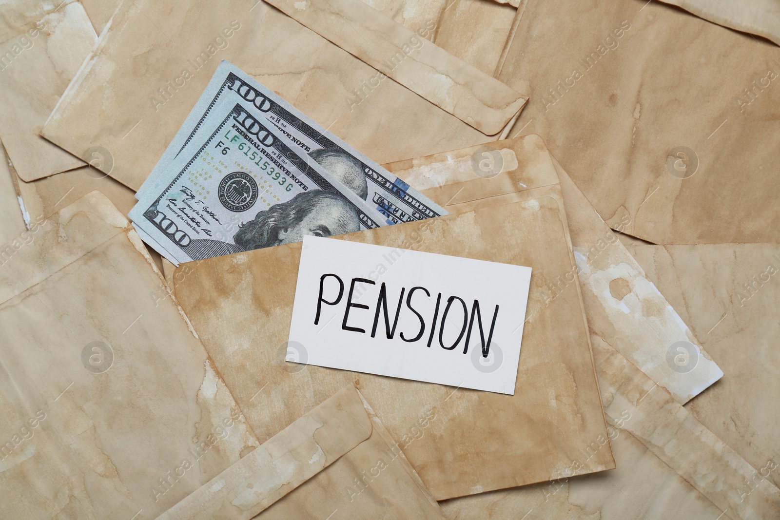 Photo of Card with word Pension and dollar banknotes on envelopes, top view