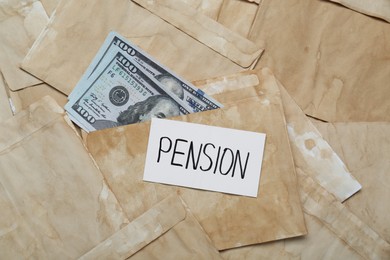 Photo of Card with word Pension and dollar banknotes on envelopes, top view