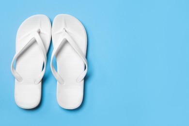 Photo of Stylish flip flops on light blue background, flat lay. Space for text