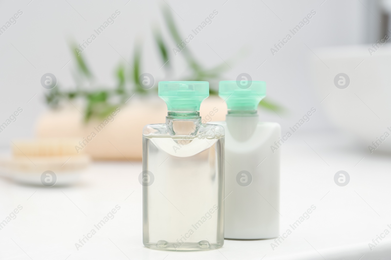 Photo of Mini bottles of cosmetic products on white table against blurred background