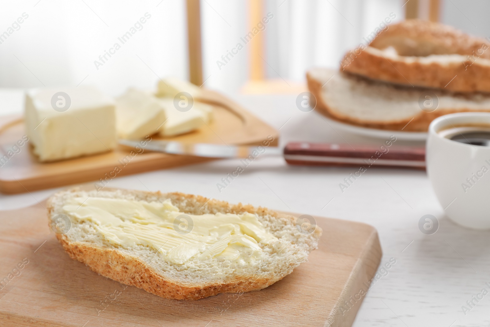 Photo of Fresh bread with tasty butter on wooden board