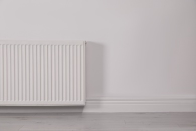 Photo of Modern radiator on white wall, space for text. Central heating system