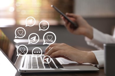 Different virtual icons and young woman using laptop and smartphone at table indoors, closeup. SMM (Social media marketing) concept