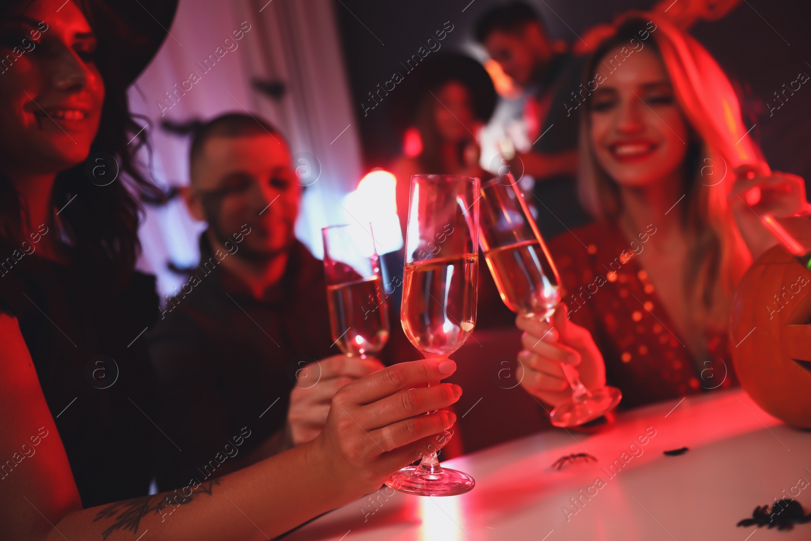 Photo of Group of friends toasting with champagne at Halloween party indoors