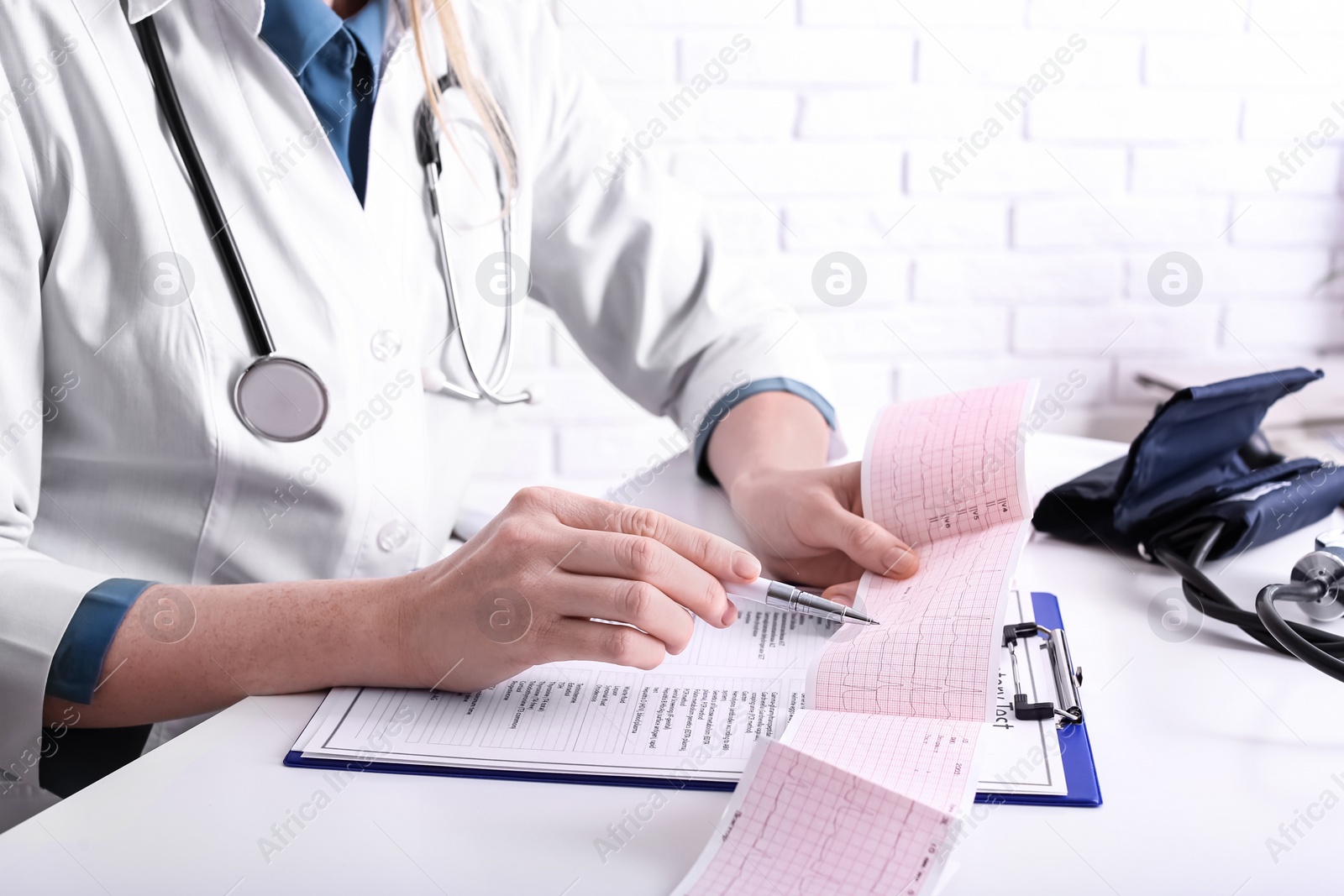 Photo of Doctor examining cardiogram at table in clinic, closeup