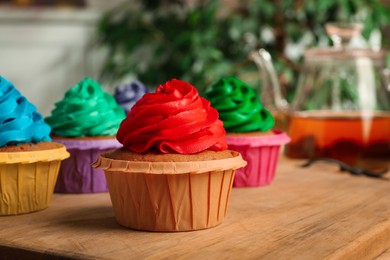 Photo of Delicious cupcakes with cream on wooden table, closeup