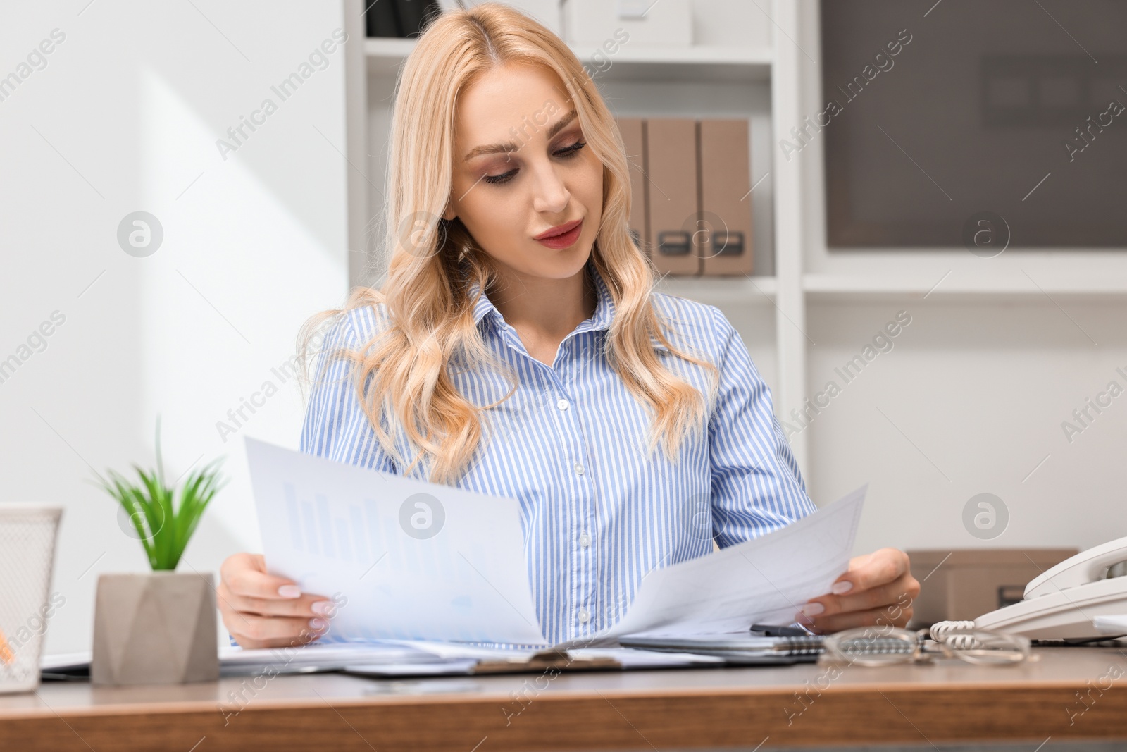 Photo of Secretary with documents at table in office