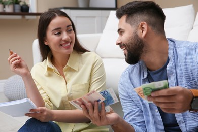 Photo of Happy couple counting money in living room