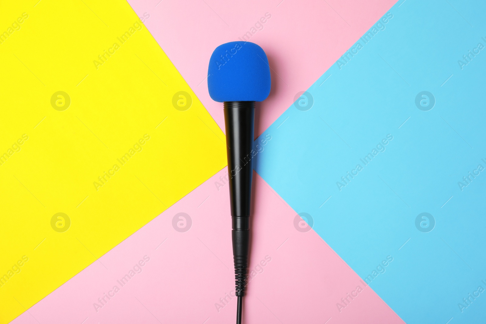 Photo of Modern microphone on color background, top view