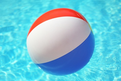 Colorful beach ball floating in swimming pool on sunny day