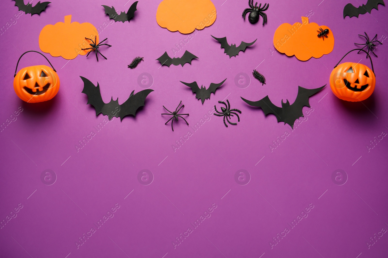 Photo of Flat lay composition with pumpkins, spiders and paper bats on purple background, space for text. Halloween celebration