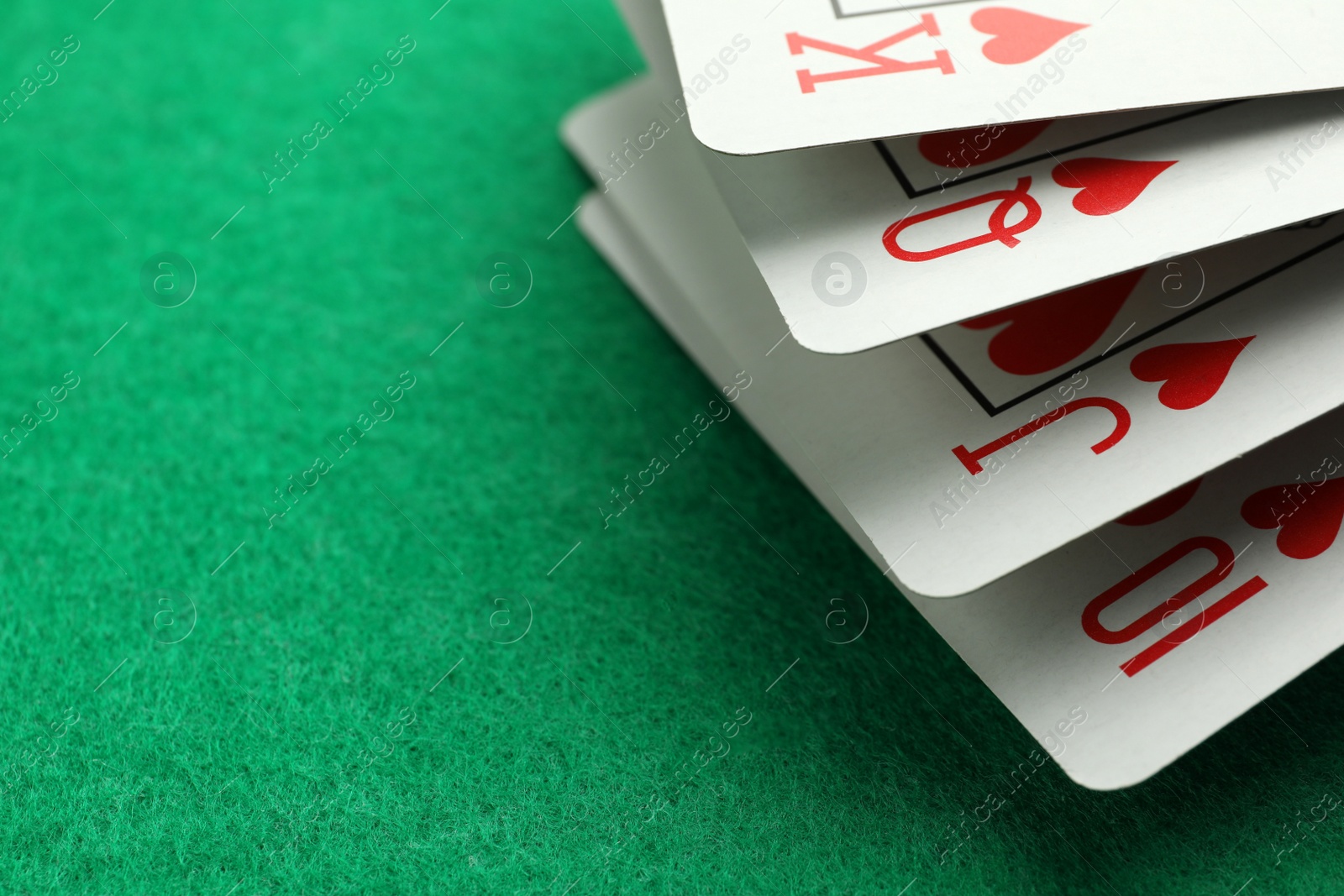 Photo of Hand of playing cards on green table, closeup. Space for text