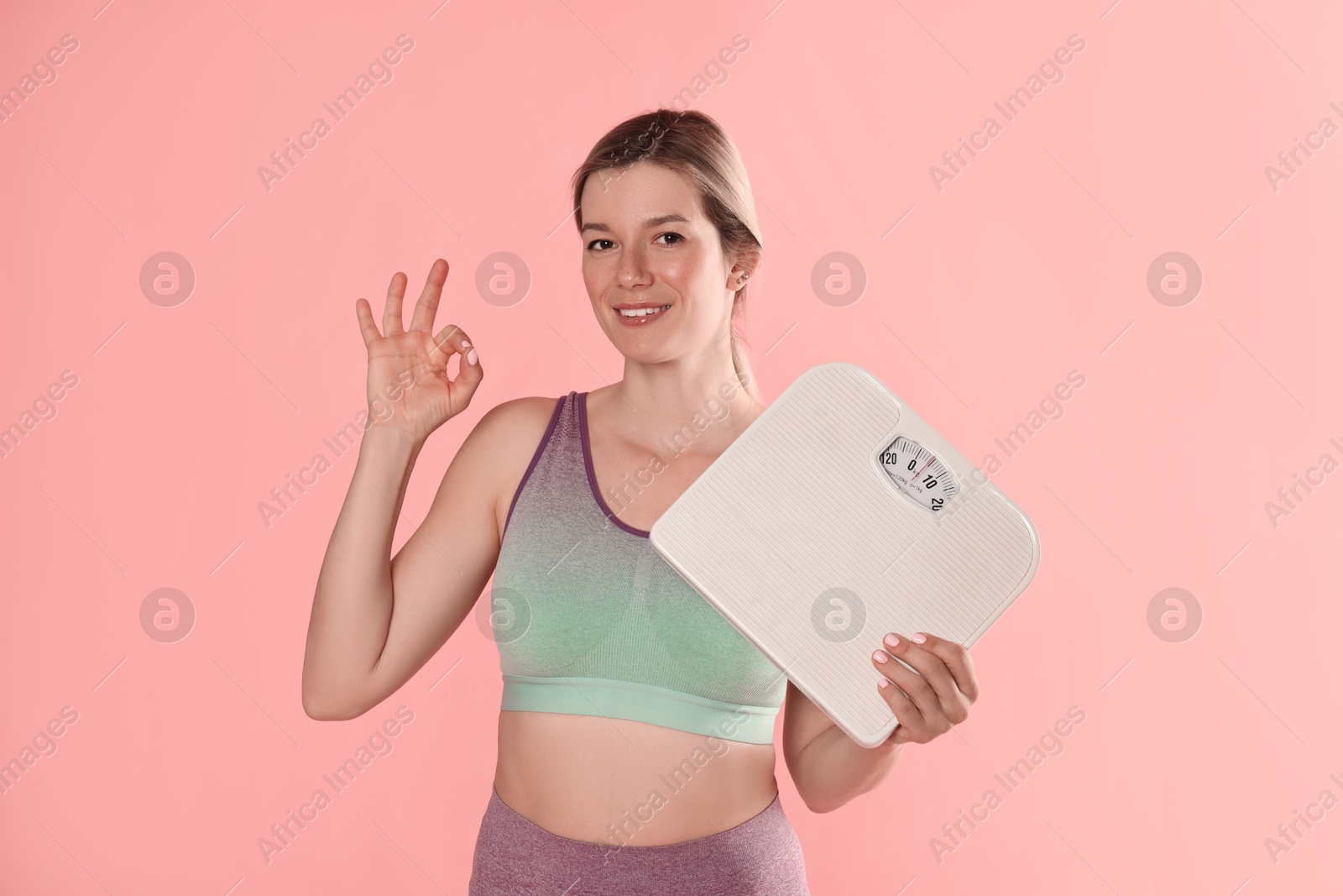 Photo of Beautiful woman with scales showing OK gesture on pink background