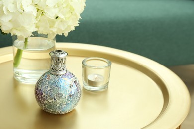 Photo of Stylish catalytic lamp with burning candle and hydrangea on golden table in living room, space for text. Cozy interior