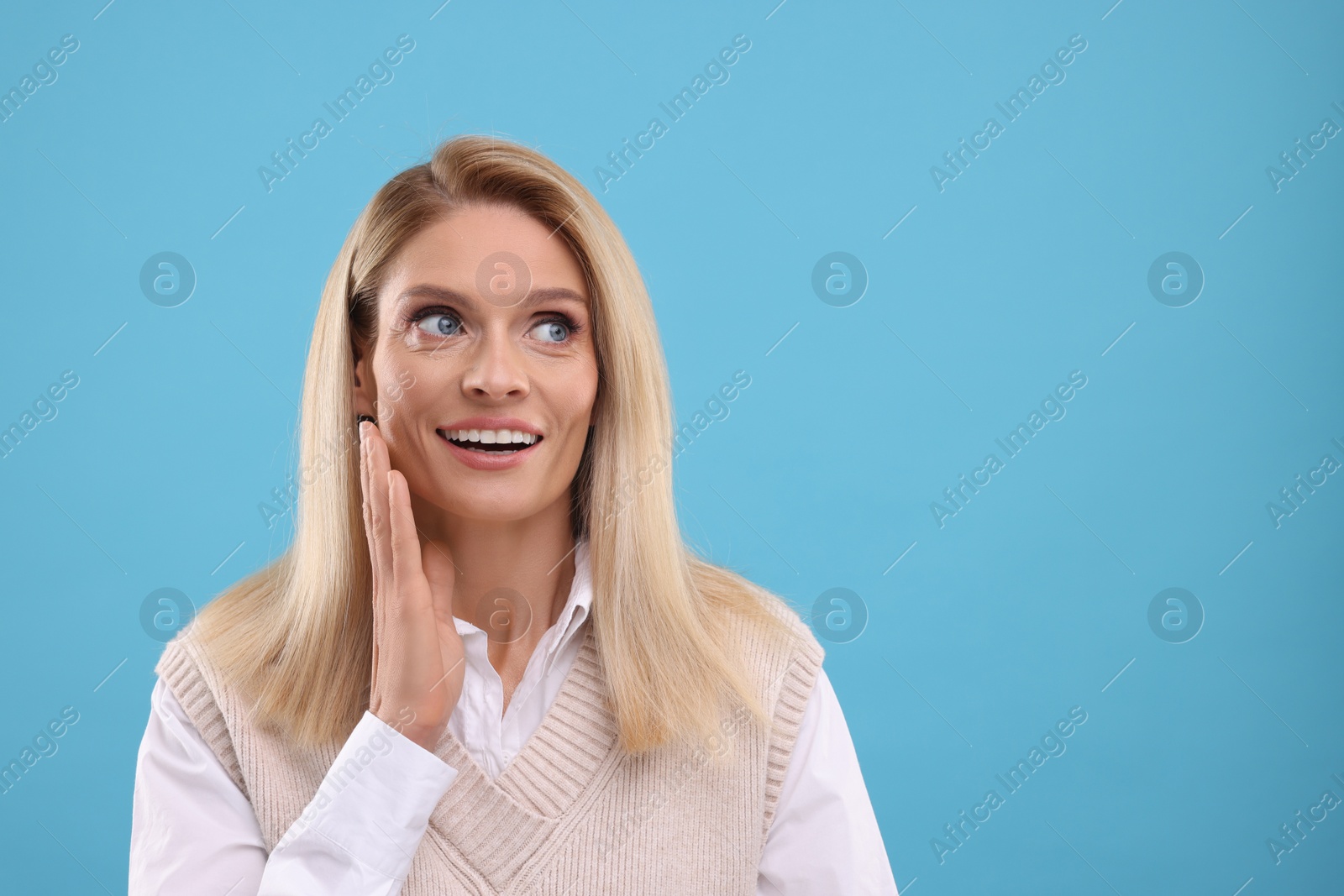 Photo of Portrait of smiling middle aged woman on light blue background. Space for text