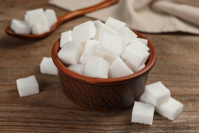 Photo of Bowl and white sugar cubes on wooden table, closeup