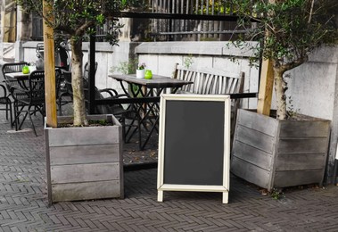 Black wooden sandwich board near outdoor cafe