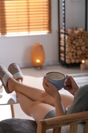 Photo of Woman with cup of aromatic coffee relaxing at home, closeup