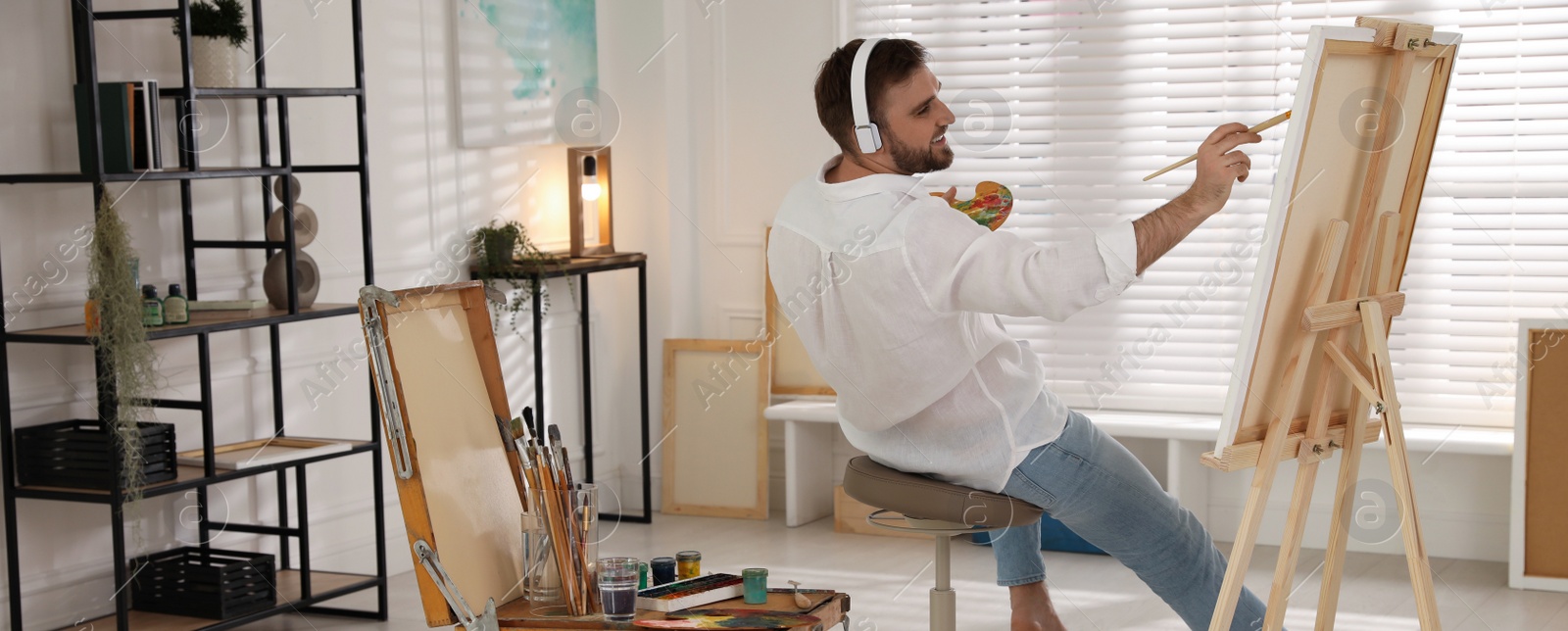 Image of Young man painting with brush in artist studio. Banner design