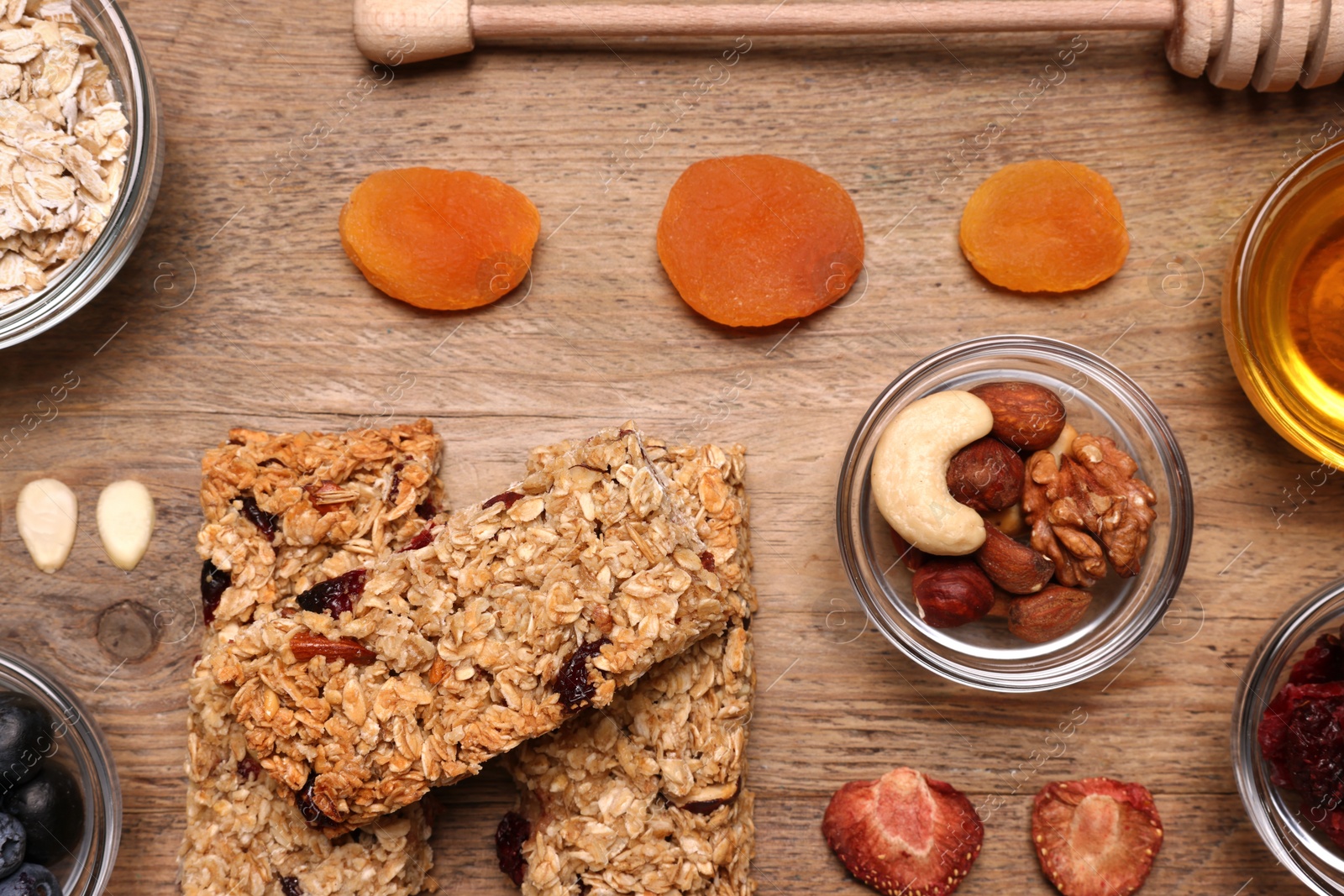 Photo of Tasty granola bars served on wooden table, flat lay