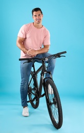 Photo of Handsome young man with modern bicycle on light blue background