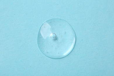Sample of cosmetic serum on light blue background, top view