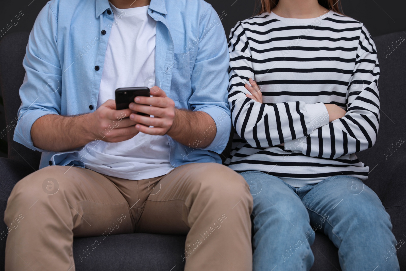 Photo of Man preferring smartphone over his girlfriend at home, closeup. Relationship problems