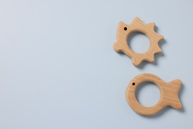 Photo of Baby accessories. Wooden teethers on light blue background, top view