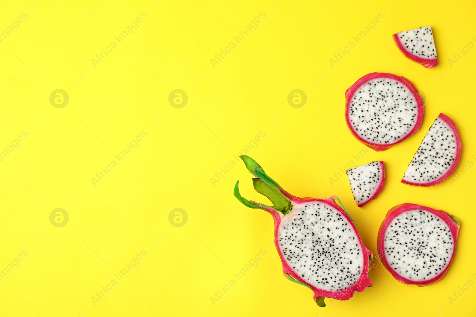 Photo of Delicious cut dragon fruit (pitahaya) on yellow background, flat lay. Space for text