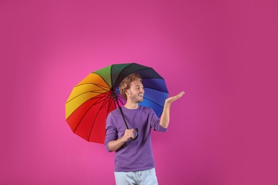 Photo of Man with rainbow umbrella on color background