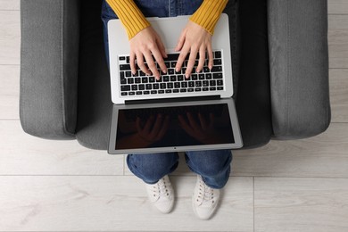 Photo of Woman working with laptop in armchair, top view