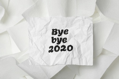 Crumpled sheet with text Bye Bye 2020 on pile of toilet paper, top view