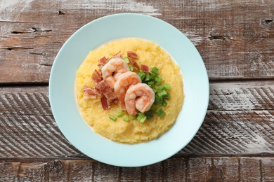 Photo of Plate with fresh tasty shrimps, bacon, grits and green onion on wooden table, top view