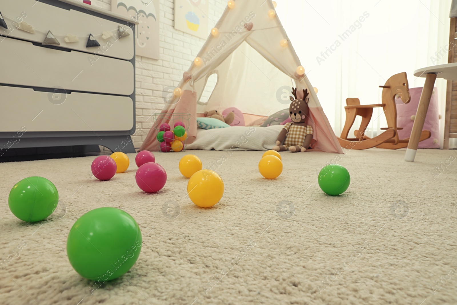 Photo of Bright toy balls near play tent on floor in child's room