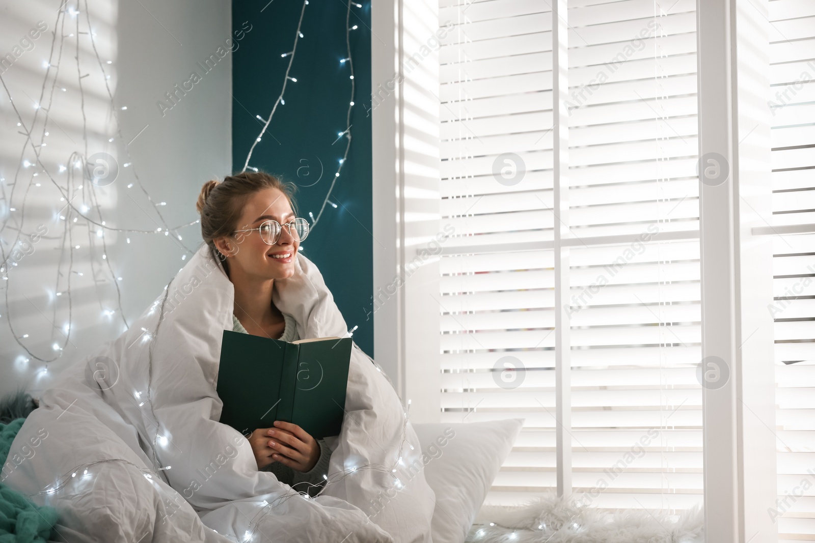 Photo of Young woman reading book at home. Cozy winter