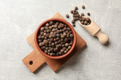 Photo of Aromatic allspice pepper grains in bowl and scoop on grey table, top view