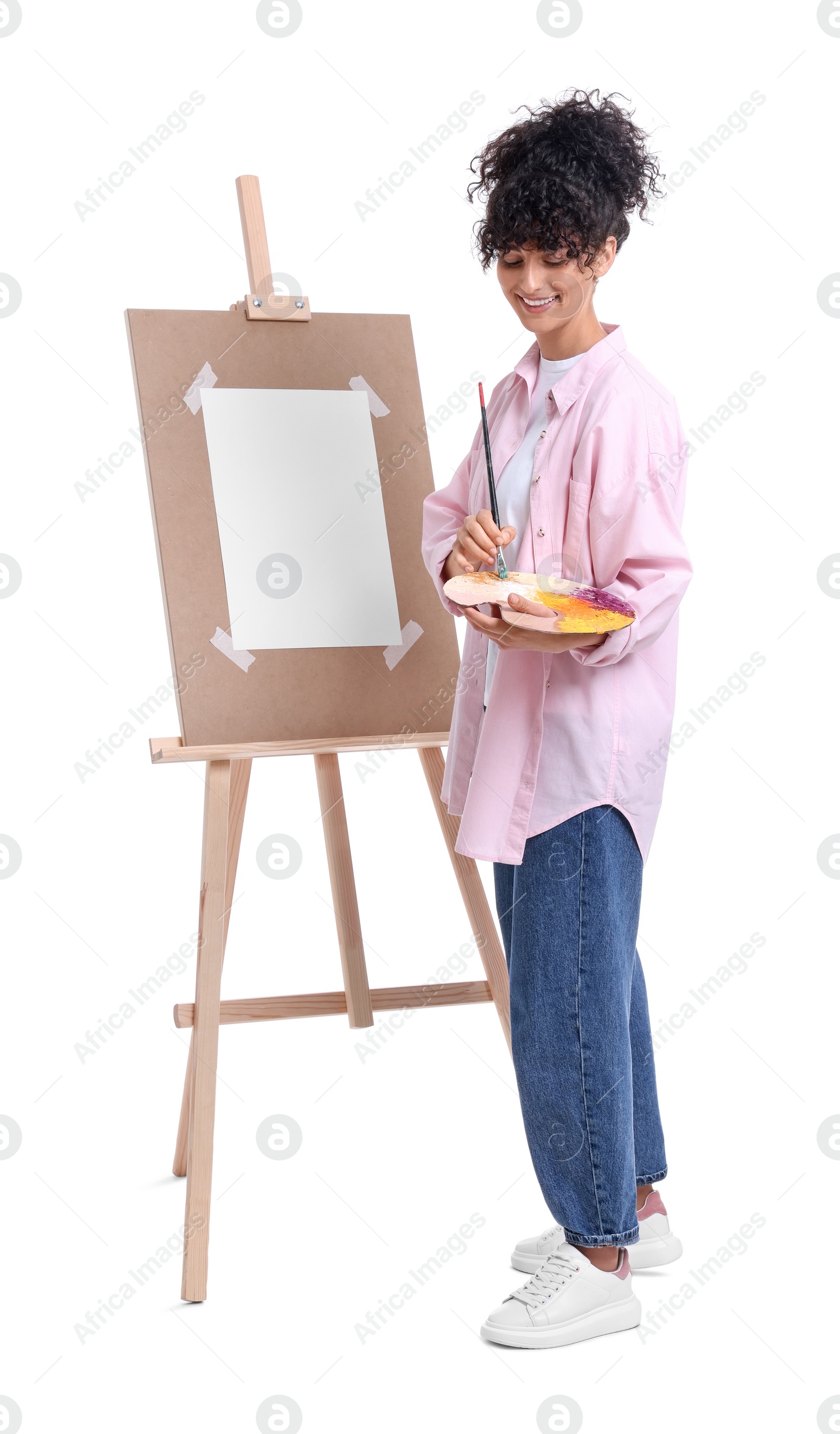 Photo of Young woman painting on easel with paper against white background