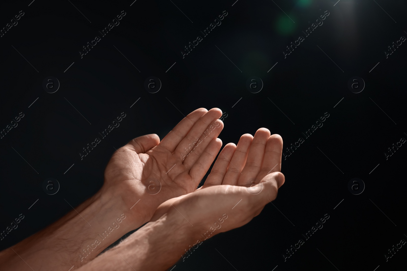 Photo of Man reaching hands to light in darkness, closeup