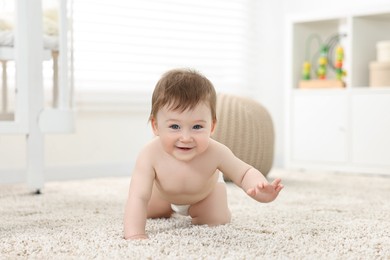 Cute baby boy crawling on carpet at home