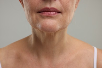 Mature woman with healthy skin on grey background, closeup