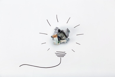 Photo of Composition with crumpled banknote and drawing of lamp bulb on white background, top view. Creative concept