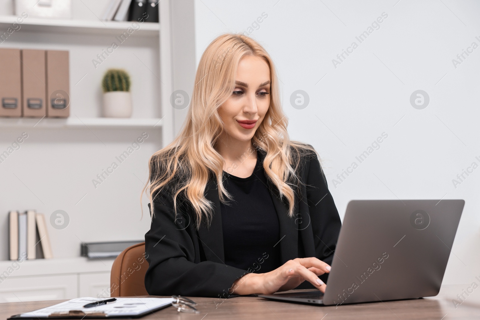 Photo of Happy secretary working with laptop in office