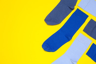 Many different blue socks on yellow background, flat lay. Space for text