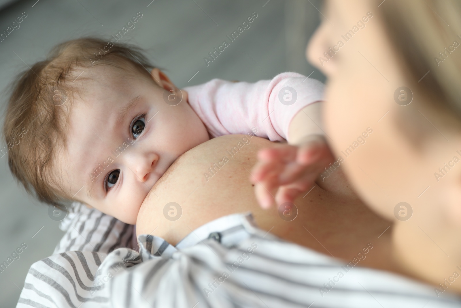 Photo of Young woman breastfeeding her baby at home, closeup