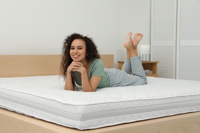 Happy young African American woman on bed with comfortable mattress at home