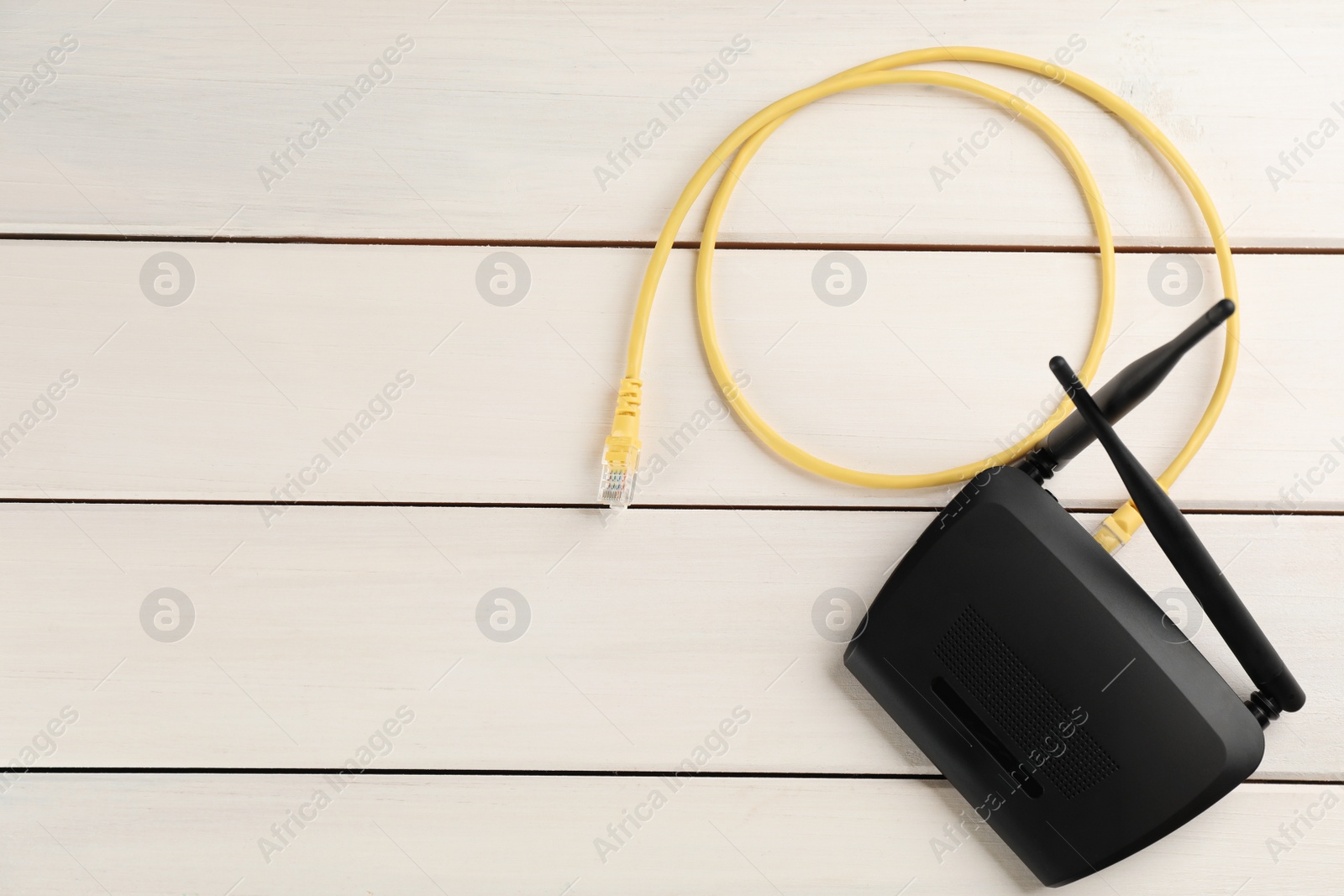 Photo of Modern Wi-Fi router on white wooden background, top view. Space for text